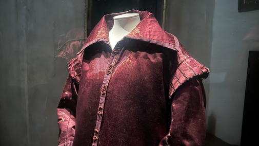 Close up image of Bess's 400 year old magenta coloured gown embellished with simple golden thread